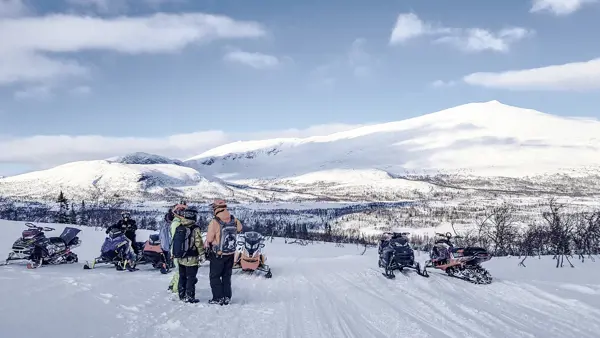Snöskoteråkare under en utbildning med fjäll i bakgrunden