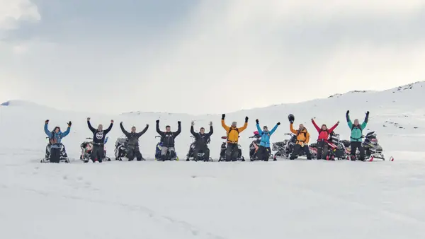 Grupp skoteråkare bredvid snöskotrar