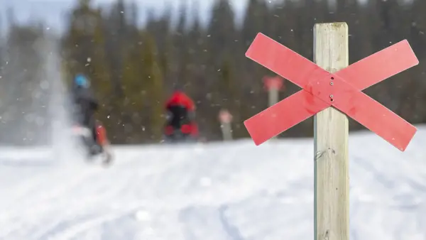 Skoterledsmarkering med snöskotrar i bakgrunden